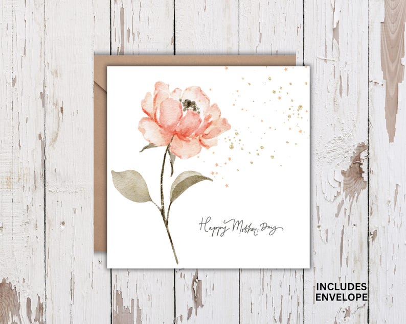Square Mother’s Day card with watercolor pink flower and gold accents shown with kraft envelope on white rustic wood background.