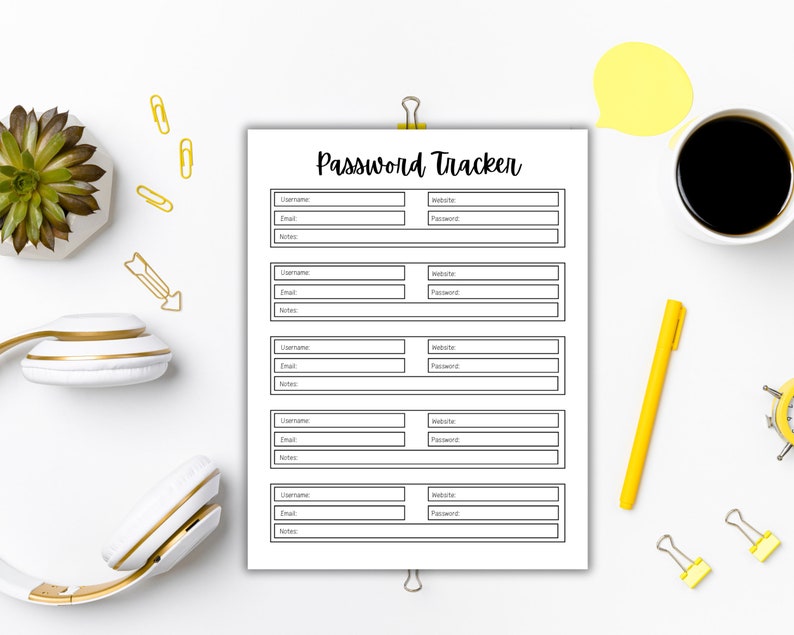 Password tracker page clipped at the top, centered on a white desk and surrounded by yellow office supplies, paper clips, a pen, a cup of black coffee, and a small plant.