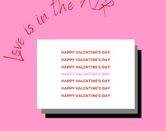May include: A white card with the text "Love is in the air" written in red cursive above it. The card has the text "Happy Valentine's Day" repeated six times in red, with the fourth instance in pink.
