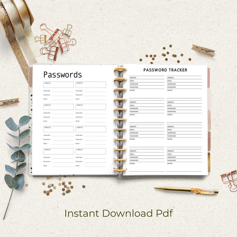 Open ring-bound planner showing two black and white password pages labeled “Passwords” and “Password Tracker,” styled on a light desk with gold binder rings, pen, paper clips, ribbon, and decorative greenery.