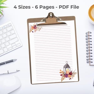 Fall stationery sheet with floral lantern design on a clipboard, surrounded by keyboard, coffee, and office supplies.