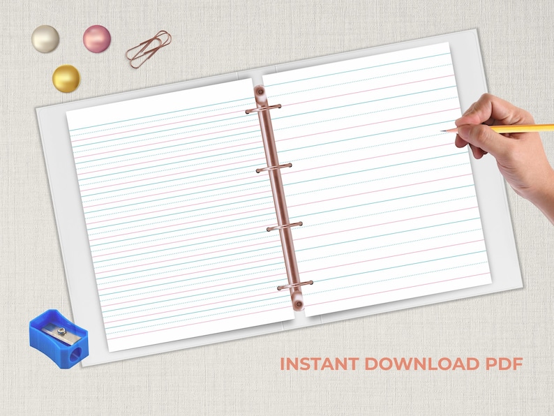 Handwriting practice paper in an open binder with a hand holding a pencil on the right.