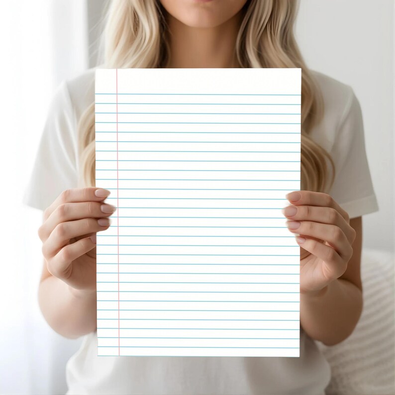 A woman holding a blue lined notebook paper sheet with a red margin line, centered in front of her torso against a bright white background.