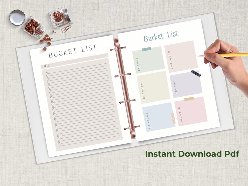 Open ring binder planner showing two bucket list pages with checklist lines and colorful note boxes while a hand holds a pencil above the page.
