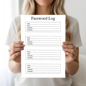 Person holding a black and white password log sheet with labeled fields for name, email, username, and password against a neutral indoor background.