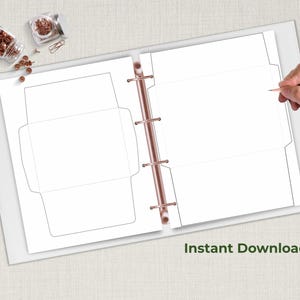 Open binder displaying two envelope template sheets with solid and dotted cut-and-fold lines, shown on a neutral desk beside stationery items.