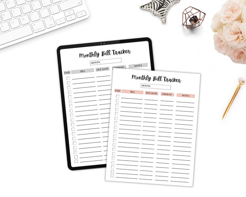 Monthly bill tracker sheets displayed on a white desk with flowers, a gold pen, and a tablet for a clean organized workspace look.