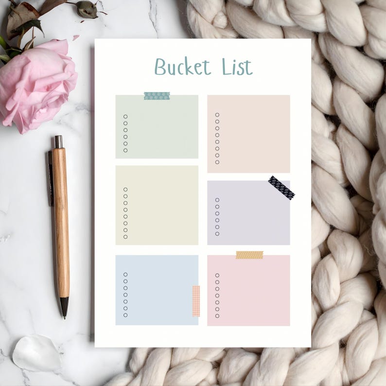 Bucket list page with six pastel-colored sections, each with checkboxes for listing goals, styled on a neutral background with a pen, pink flower, and soft textured blanket.