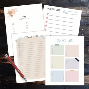Four bucket list planner pages with checklist lines and colorful note boxes arranged on a dark wooden surface with a red pen beside the pages.