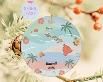 May include: A round ceramic ornament featuring a map of Hawaii with palm trees and flowers. The ornament has a light blue, pink, and green color scheme. The word "Oahu" and "Hawaii 2025" are printed on the ornament.