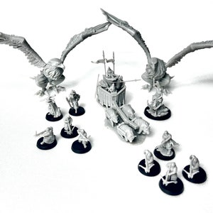 Puede incluir: Un conjunto de figuras en miniatura que representan un carro de guerra tirado por cuatro jabalíes, con dos criaturas parecidas a águilas flanqueando el carro. Las figuras están pintadas de gris y se colocan sobre bases negras.