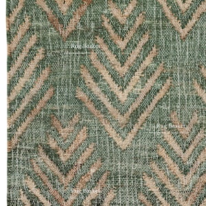 May include: Green and beige chevron patterned rug with a textured weave. The rug features a repeating V-shaped design in shades of green and beige. The bottom edge has a fringe.