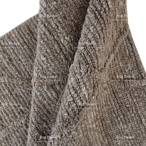 May include: Close-up of a brown, textured rug with a woven design. The rug is made of natural fibres and has a soft, fluffy texture.
