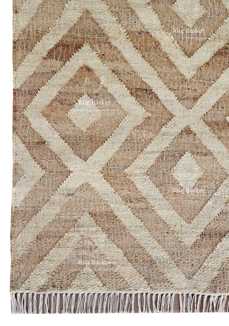 May include: Close-up of a natural fiber rug with a geometric diamond pattern. The rug features alternating shades of beige and brown, creating a textured, woven design. The edge has a fringe detail.