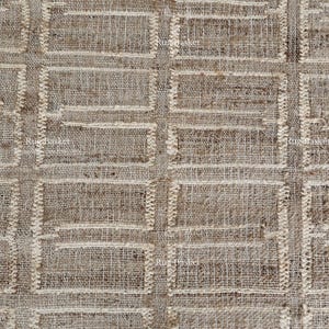 May include: Close-up of a woven textile with a repeating rectangular pattern. The fabric has a natural, neutral colour palette with a textured appearance. The design features a grid of rectangles.