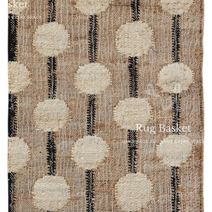 Puede incluir: Una alfombra rectangular con tejido de yute natural, con un patrón de círculos color crema y rayas negras verticales. La alfombra tiene un borde con flecos y el texto "Rug Basket" es visible.