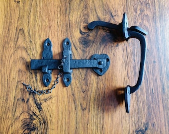 Peut inclure: Loquet de porte en métal noir avec une chaîne et une poignée séparée. Le loquet a une barre rectangulaire avec un crochet à une extrémité et une plaque carrée à l'autre. La poignée est une pièce de métal incurvée avec une boucle à l'extrémité.
