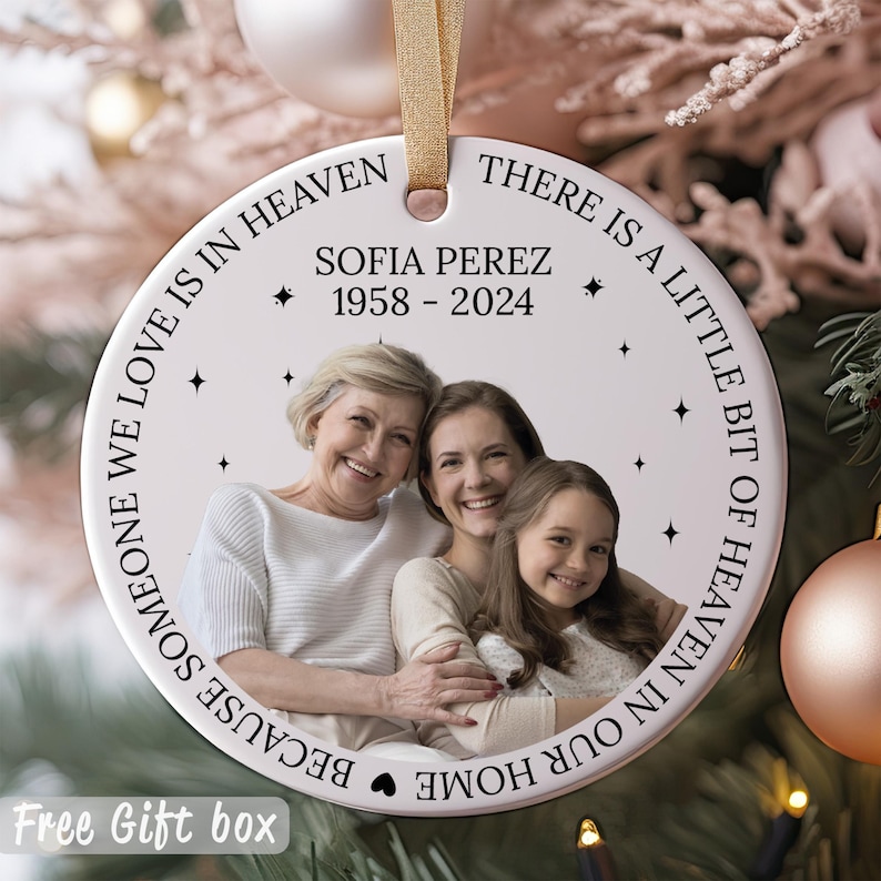 May include: White ceramic ornament with a photo of three people and the text "THERE IS A LITTLE BIT OF HEAVEN IN OUR HOME BECAUSE SOMEONE WE LOVE IS IN HEAVEN SOFIA PEREZ 1958-2024".