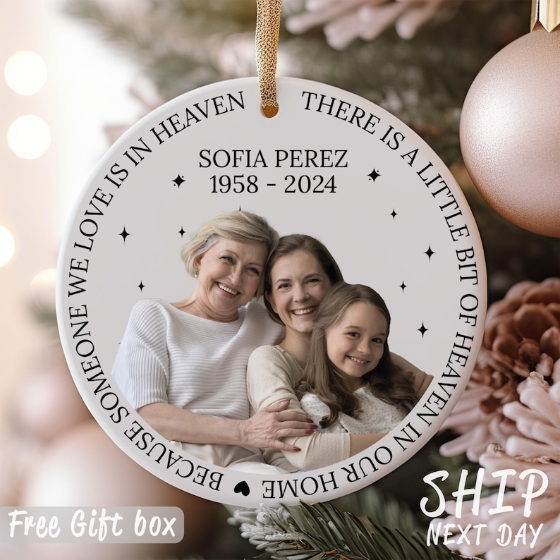 May include: White ceramic ornament with a photo of three people and the text "Because someone we love is in heaven there is a little bit of heaven in our home". The text also includes "Sofia Perez 1958-2024".