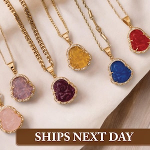 May include: Gold-toned necklaces with Buddha pendants in various colors, including red, yellow, blue, and purple. Each pendant is outlined with small, clear stones. The image also includes the text "SHIPS NEXT DAY".