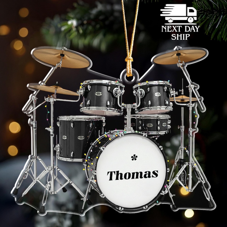 May include: A miniature drum set ornament with a personalized bass drum that reads "Thomas". The black drums have silver hardware and are accented with gold-colored cymbals. The ornament is designed to hang.