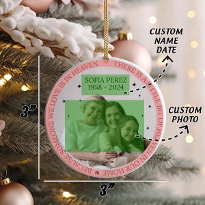 May include: A 3-inch round white ceramic ornament with a pink border. The ornament features a photo of three women, a quote that reads "There is a little bit of heaven in our home because someone we love is in heaven", and the text "Sofia Perez 1958-2024".