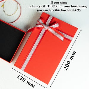 a red gift box with a ribbon and a pair of glasses