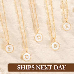May include: Five gold necklaces with white round pendants featuring the letters A, B, C, D, and E. The necklaces are on a white background.