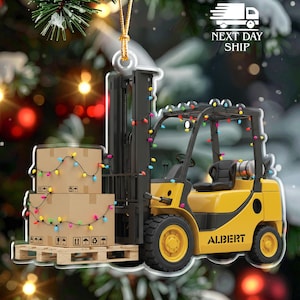May include: A yellow forklift Christmas ornament with a black cab and a pallet of cardboard boxes. The boxes are decorated with a string of colorful lights. The ornament has the word "ALBERT" on the side.
