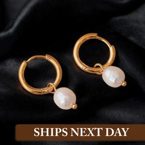 May include: A pair of gold hoop earrings with a single pearl dangling from each hoop.