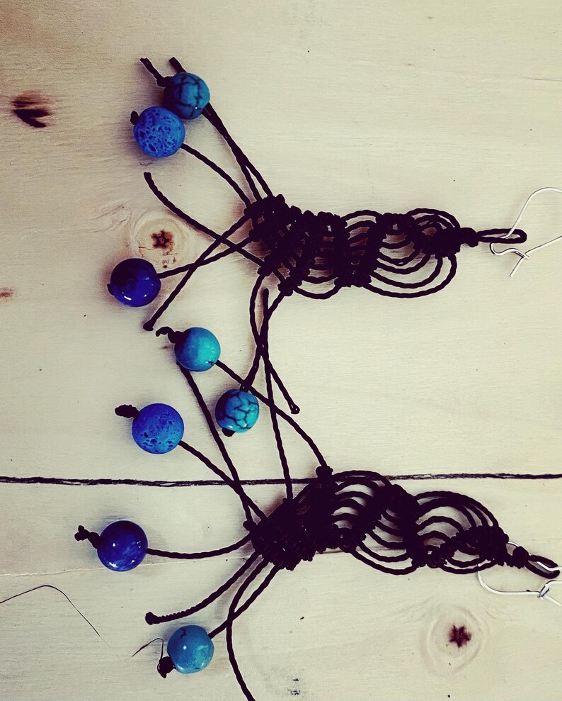 May include: A pair of handmade earrings with black macrame and turquoise and blue beads.