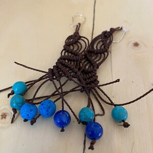 May include: A pair of brown macrame earrings with turquoise and blue beads.