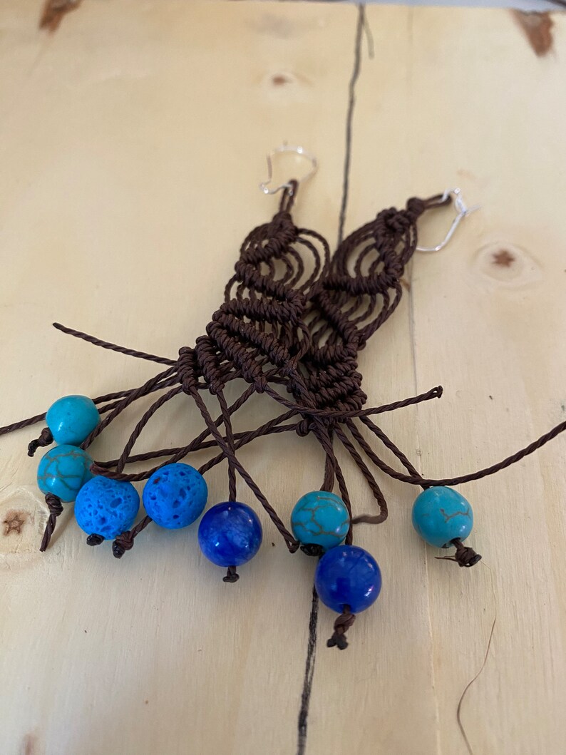May include: A pair of brown macrame earrings with turquoise and blue beads.