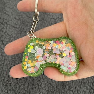May include: A green glitter filled game controller keyring with a silver chain.