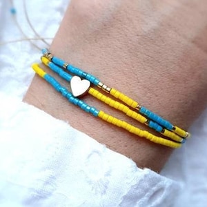 May include: A bracelet with three strands of yellow and blue beads, with a small gold heart charm.