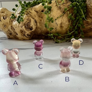 May include: Four small, clear resin bear figurines with pink and white swirls. The bears are labeled A, B, C, and D.