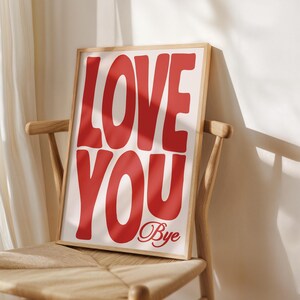 K&ouml;nnte beinhalten: Ein gerahmter Druck mit den Worten "LOVE YOU Bye" in gro&szlig;en, roten, fetten Buchstaben auf wei&szlig;em Hintergrund.