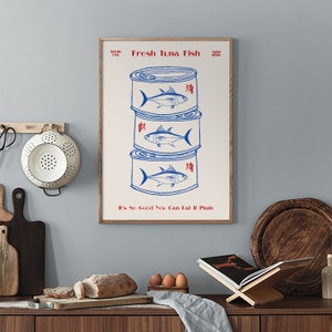 May include: A framed print featuring a stack of three blue and white tuna fish cans. The text "Fresh Tuna Fish" and "It's So Good You Can Eat It Plain" are printed in red. The net weight is 7 oz.