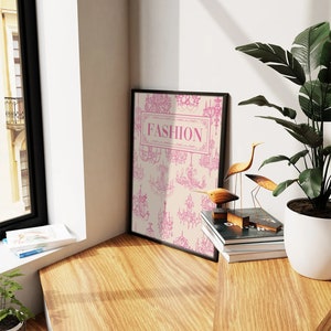 May include: A black framed print with a cream background and pink chandelier illustrations. The print has the word "FASHION" in a pink rectangle.