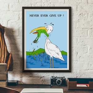 May include: A framed cartoon illustration of a white bird with a long beak holding a green frog in its beak. The bird is standing in a blue pond with green reeds. The text "NEVER EVER GIVE UP!" is printed in black at the top of the image.