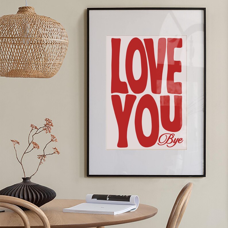 K&ouml;nnte beinhalten: Ein gerahmter Druck mit wei&szlig;em Hintergrund und rotem Text, der "LOVE YOU" sagt, mit dem Wort "Bye" in kleinerer Schrift darunter. Der Rahmen ist schwarz.
