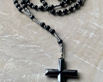 May include: A black and silver beaded rosary with a large black cross pendant.