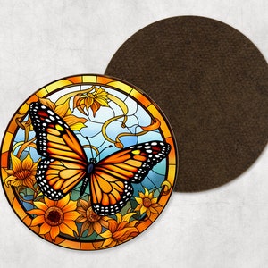 May include: Round coaster featuring a stained-glass design of a monarch butterfly with orange, black, and white wings, surrounded by yellow sunflowers and foliage. A second, plain brown coaster is next to it.