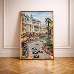 May include: A framed painting depicts a Formula 1 race in Monaco. The artwork showcases race cars speeding along a winding track lined with spectators and buildings. The painting is set in a gold frame and leans against a white wall and wooden floor.