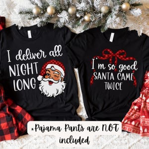 May include: Two black t-shirts with festive Christmas designs. One features the text "I deliver all NIGHT LONG" and a winking Santa Claus. The other says "I'm so good SANTA CAME TWICE" with a red bow graphic.