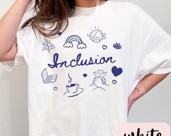 May include: White t-shirt with a blue graphic design that says "Inclusion" and features various symbols like a rainbow, a coffee cup, a handshake, and a laptop.