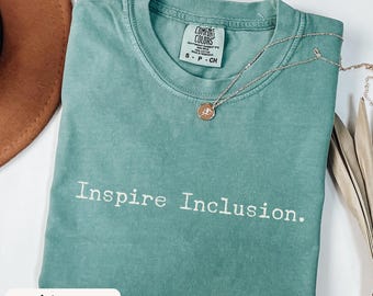 May include: Light green t-shirt with the text "Inspire Inclusion." printed in white. The shirt is made of a soft, comfortable material.