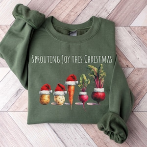 May include: A green sweatshirt with the text "Sprouting Joy This Christmas" and a graphic of vegetables wearing Santa hats.
