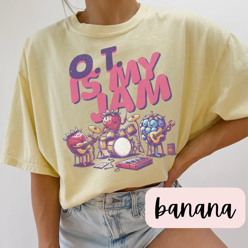 May include: A yellow t-shirt with a graphic of fruit playing instruments. The text on the shirt reads "O.T. is my jam".
