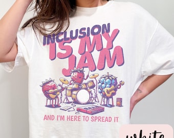 Puede incluir: Camiseta blanca con un gráfico de frutas tocando instrumentos. El texto "Inclusion is my jam and I'm here to spread it" está impreso en la camiseta.
